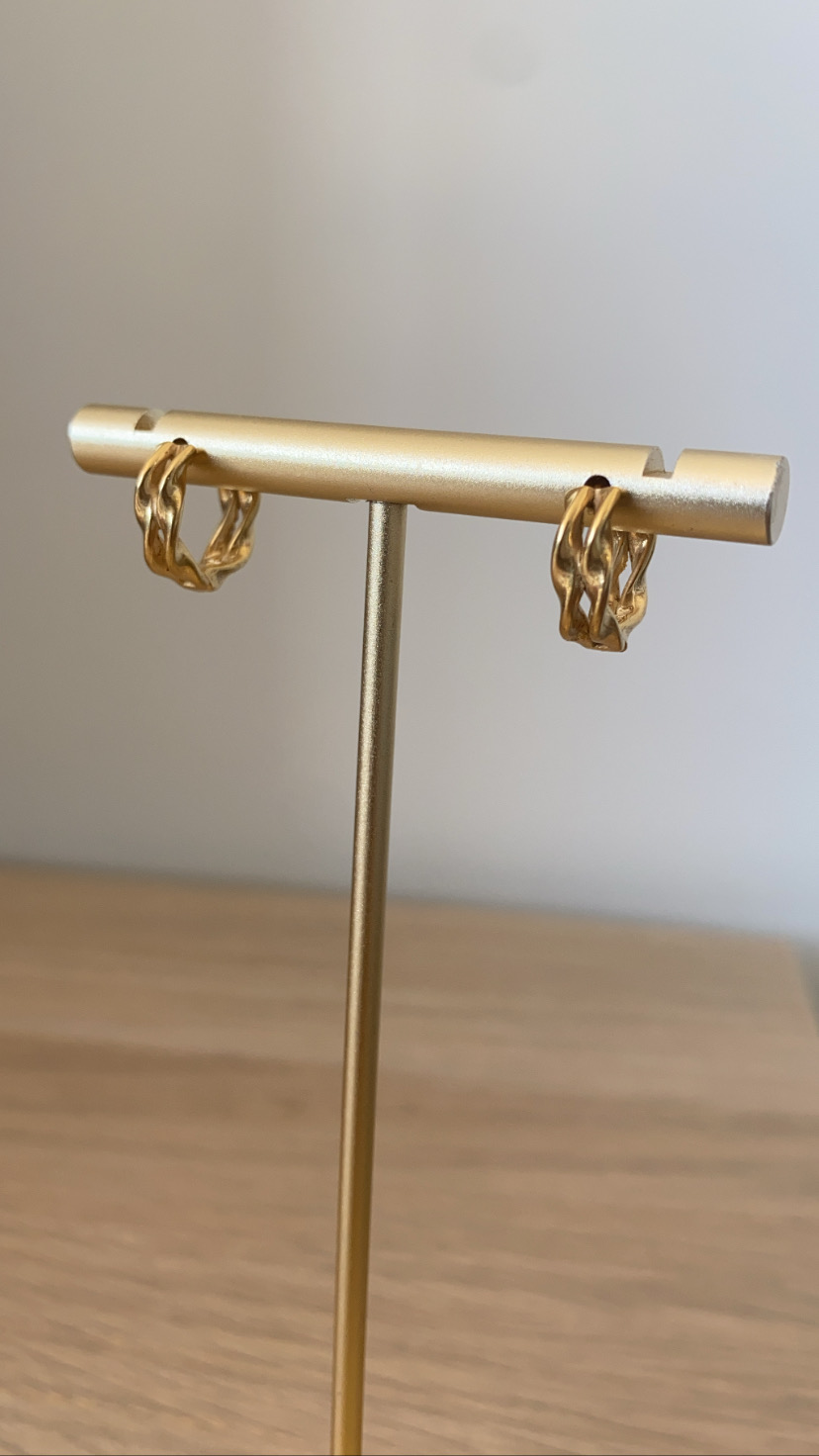 Brincos dourados entrelaçados em suporte dourado
