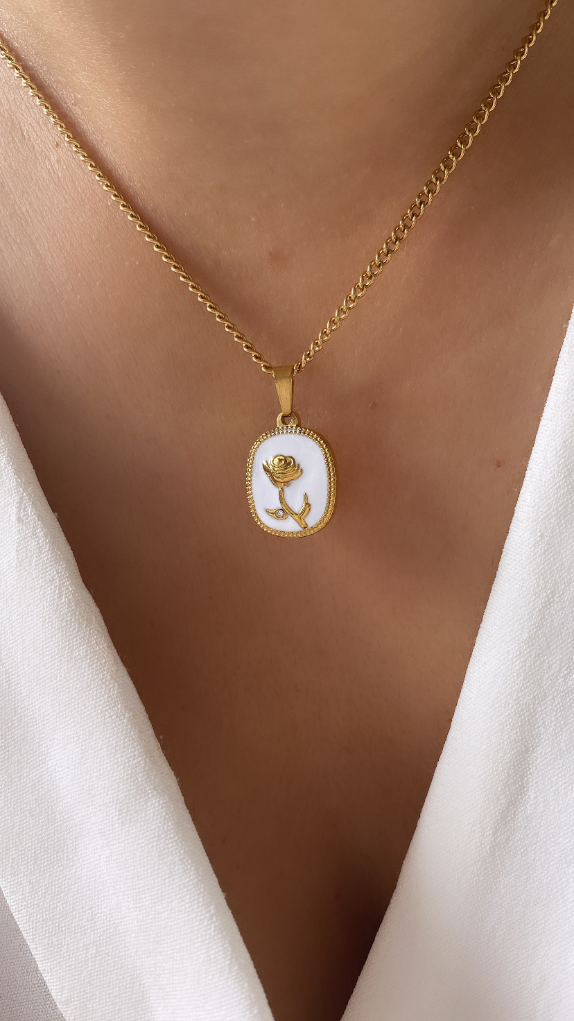 Colar dourado com pendente branco e desenho de rosa em relevo