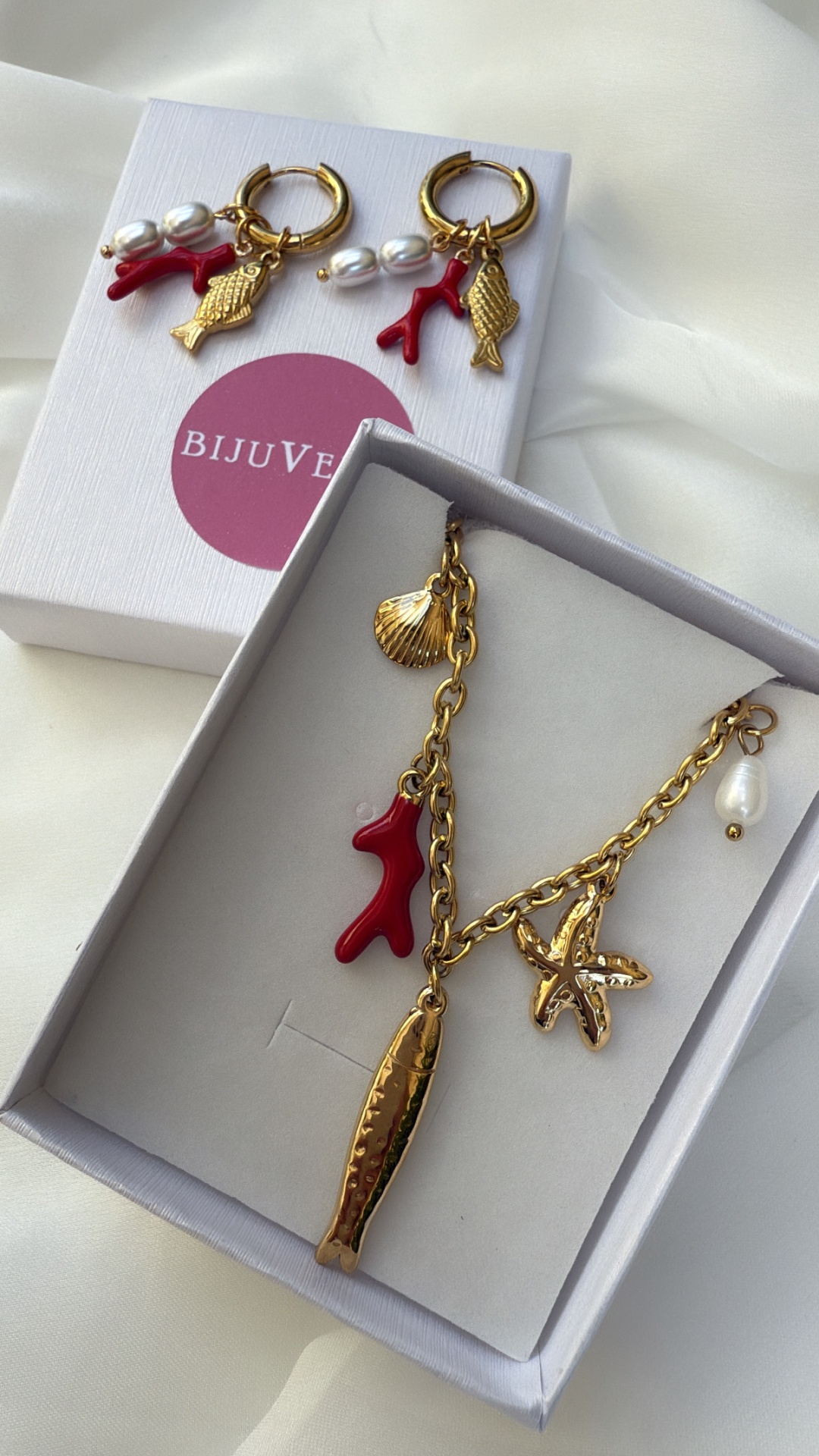 Conjunto de joias douradas com pingentes marinhos e pérolas em caixas brancas