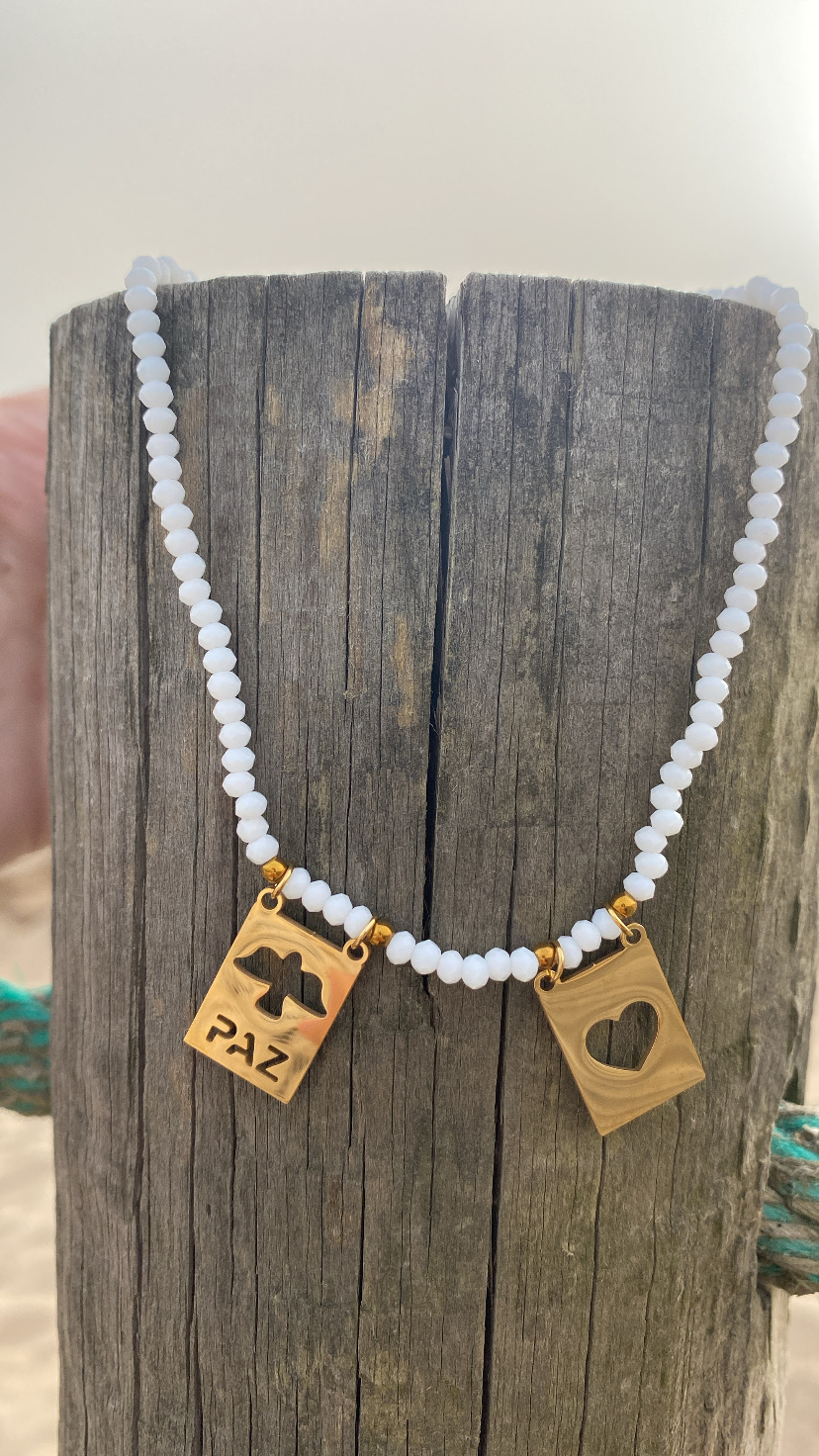 Colar de contas brancas com pendentes de madeira retangulares com a palavra PAZ e coração