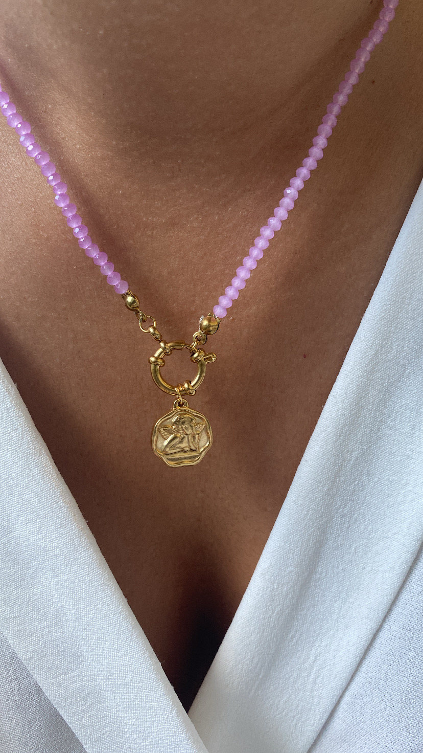 Colar com contas lilás e pendente dourado, usado com roupa branca