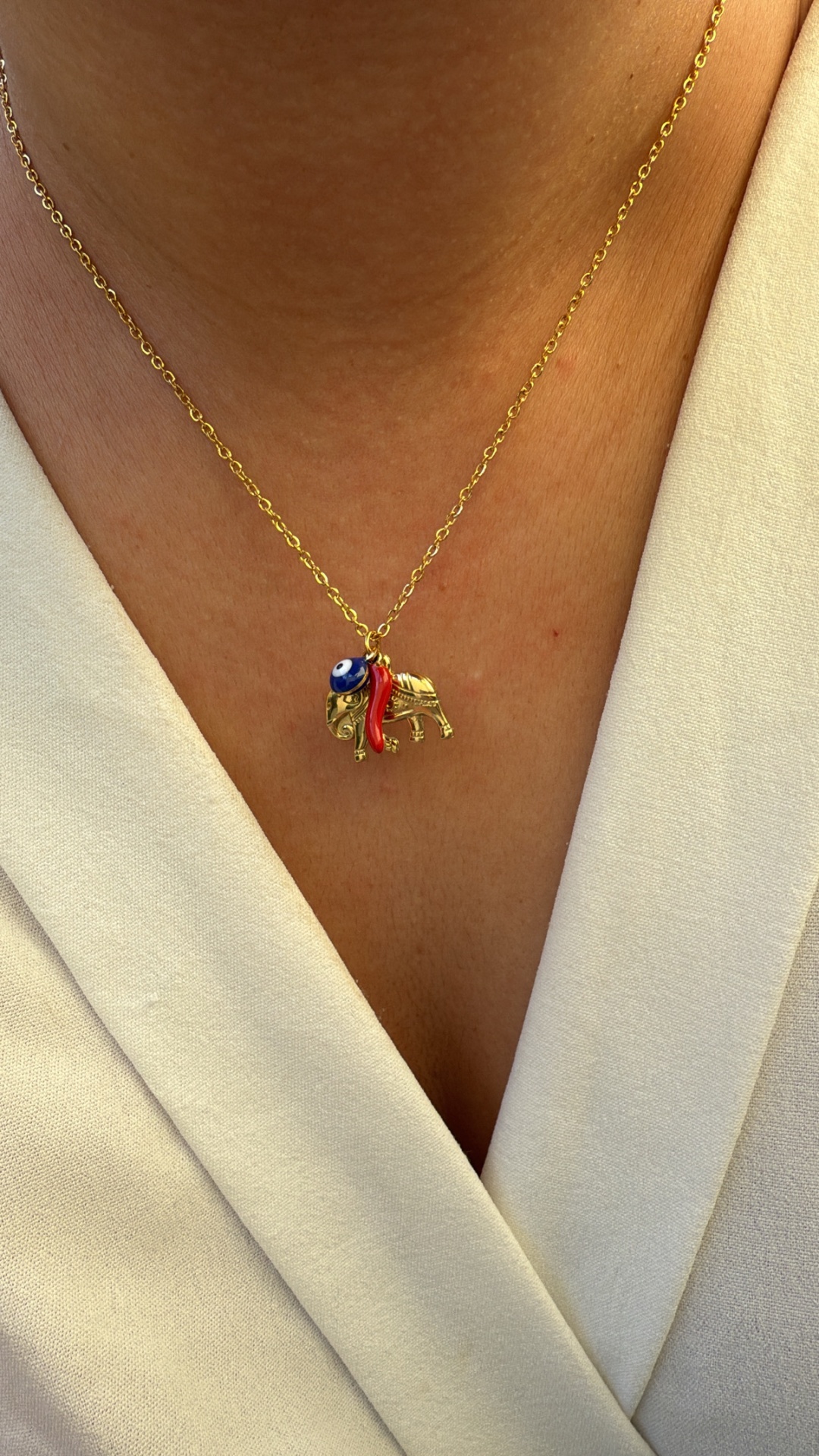 Colar dourado com pendente de elefante azul e vermelho