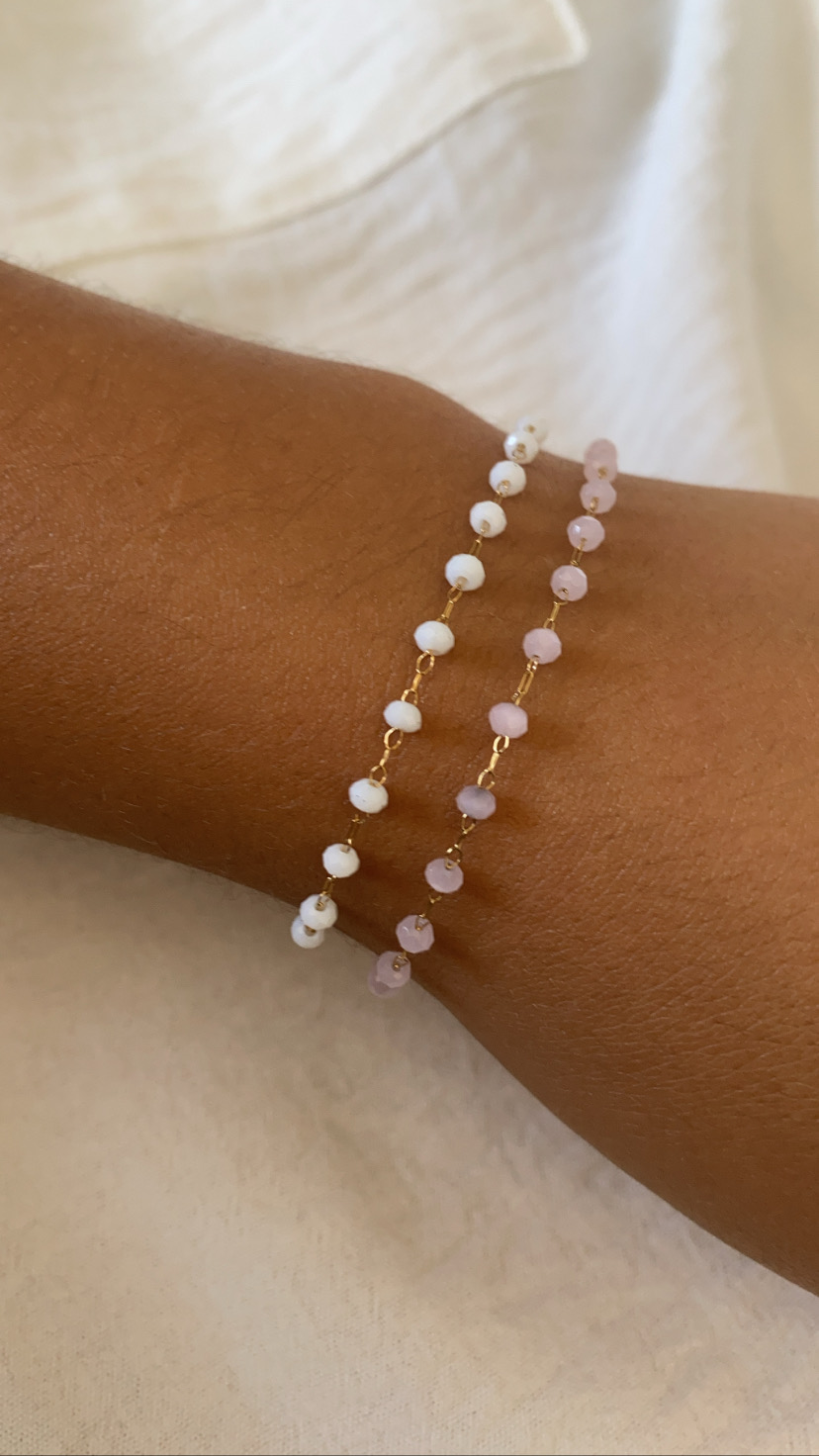 braceletes dourados com contas brancas e cor-de-rosa no pulso