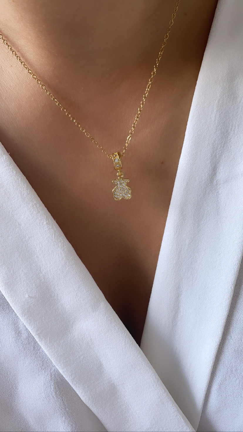 Colar dourado com pendente de ursinho cravejado usado no pescoço