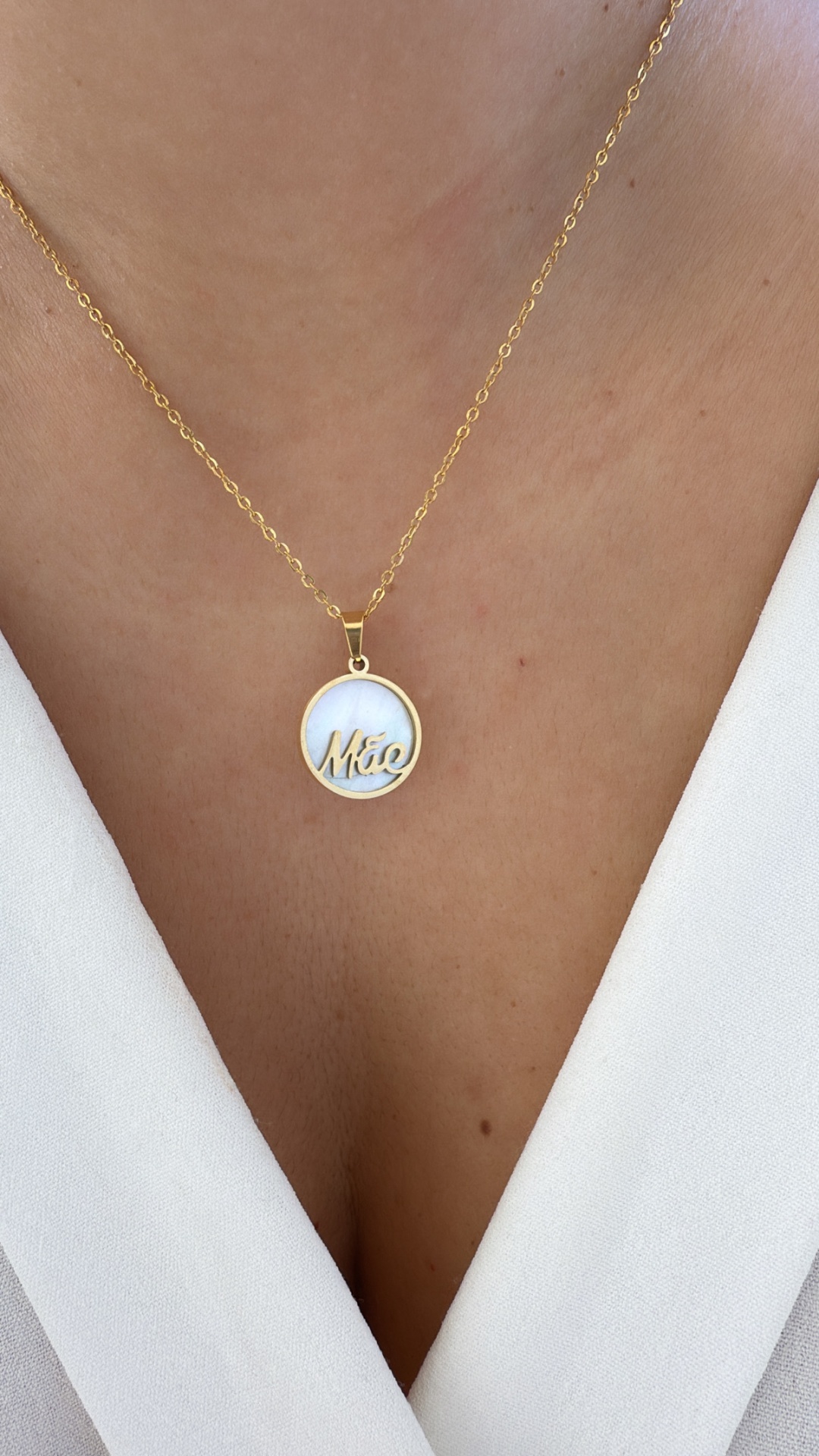 Colar dourado com pendente redondo branco e palavra 'Mãe'