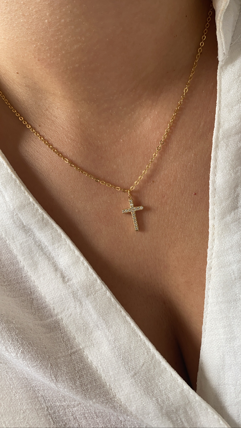 Colar dourado com pendente de cruz e camisa branca