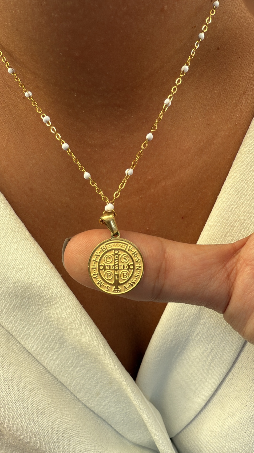 Colar dourado com pendente redondo e corrente com contas brancas