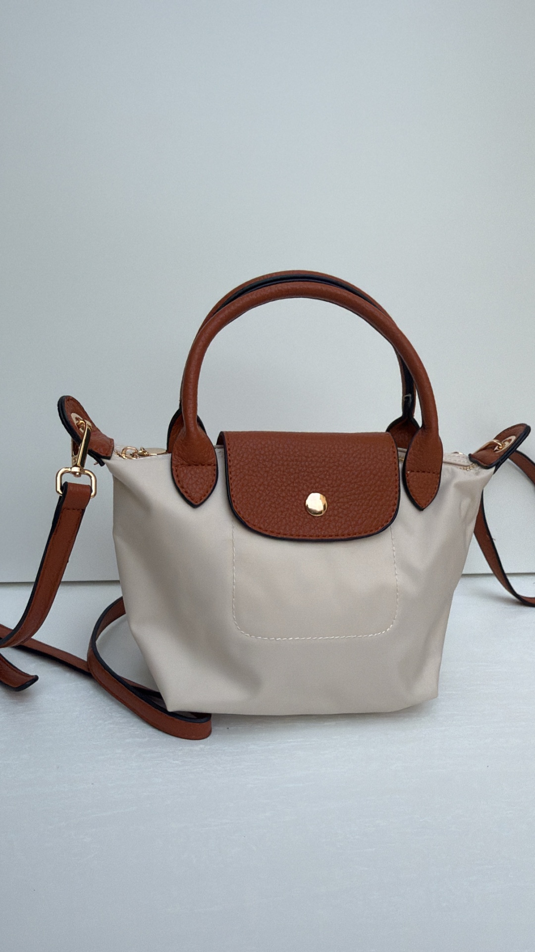 Bolsa pequena bege com detalhes castanhos e fecho dourado