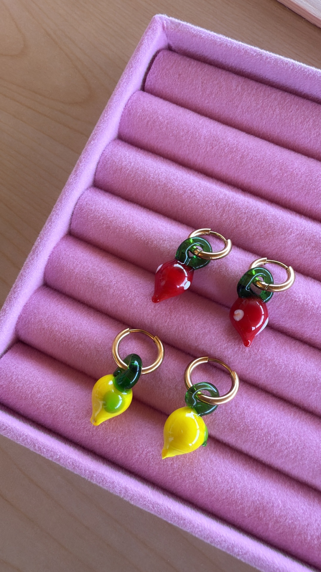 Quatro brincos com pendentes de pimento em caixa rosa aveludada