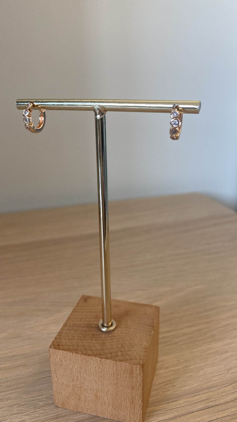 Par de brincos dourados em suporte metálico com base de madeira