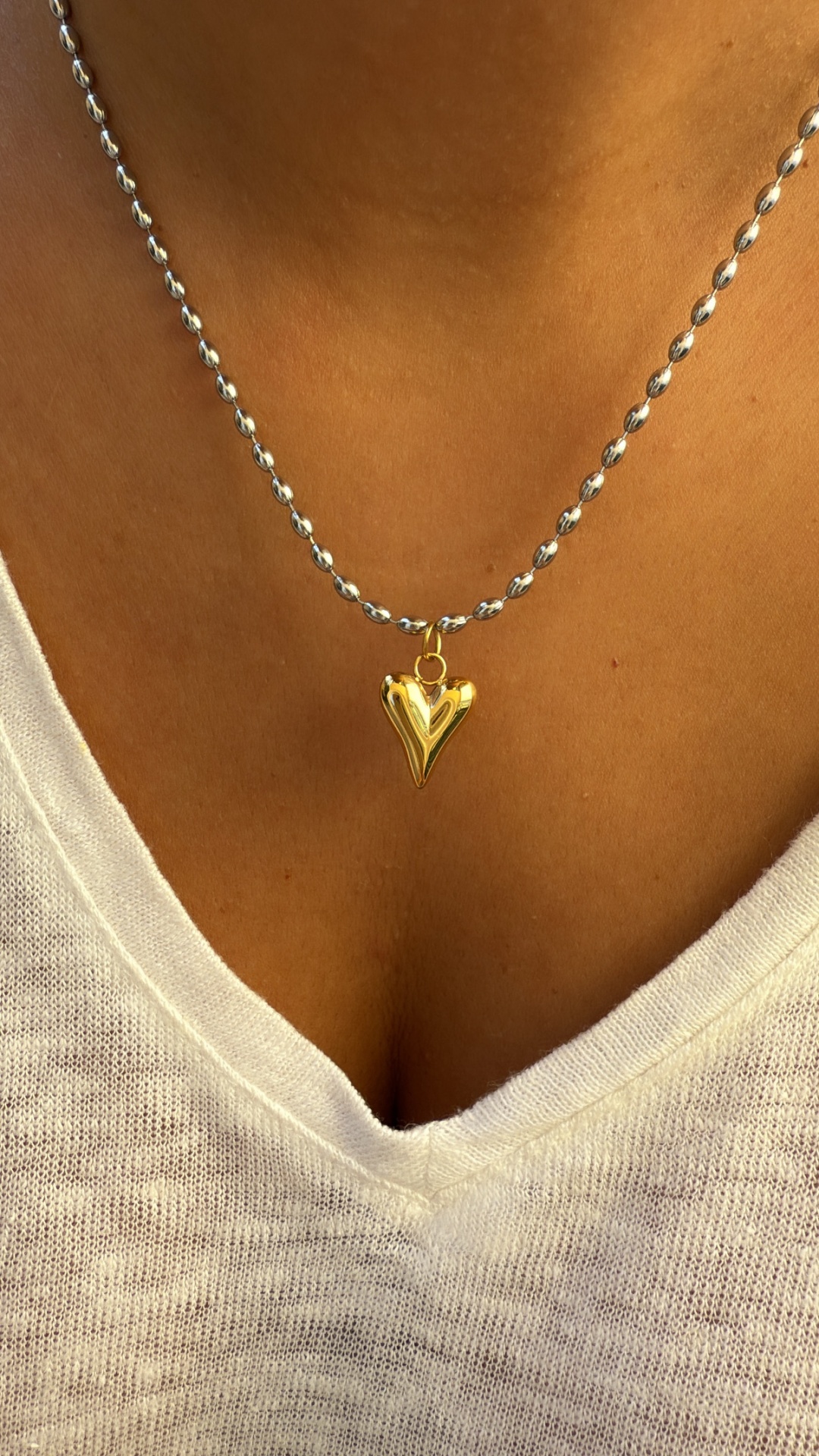 Colar com pendente dourado em forma de coração e corrente prateada