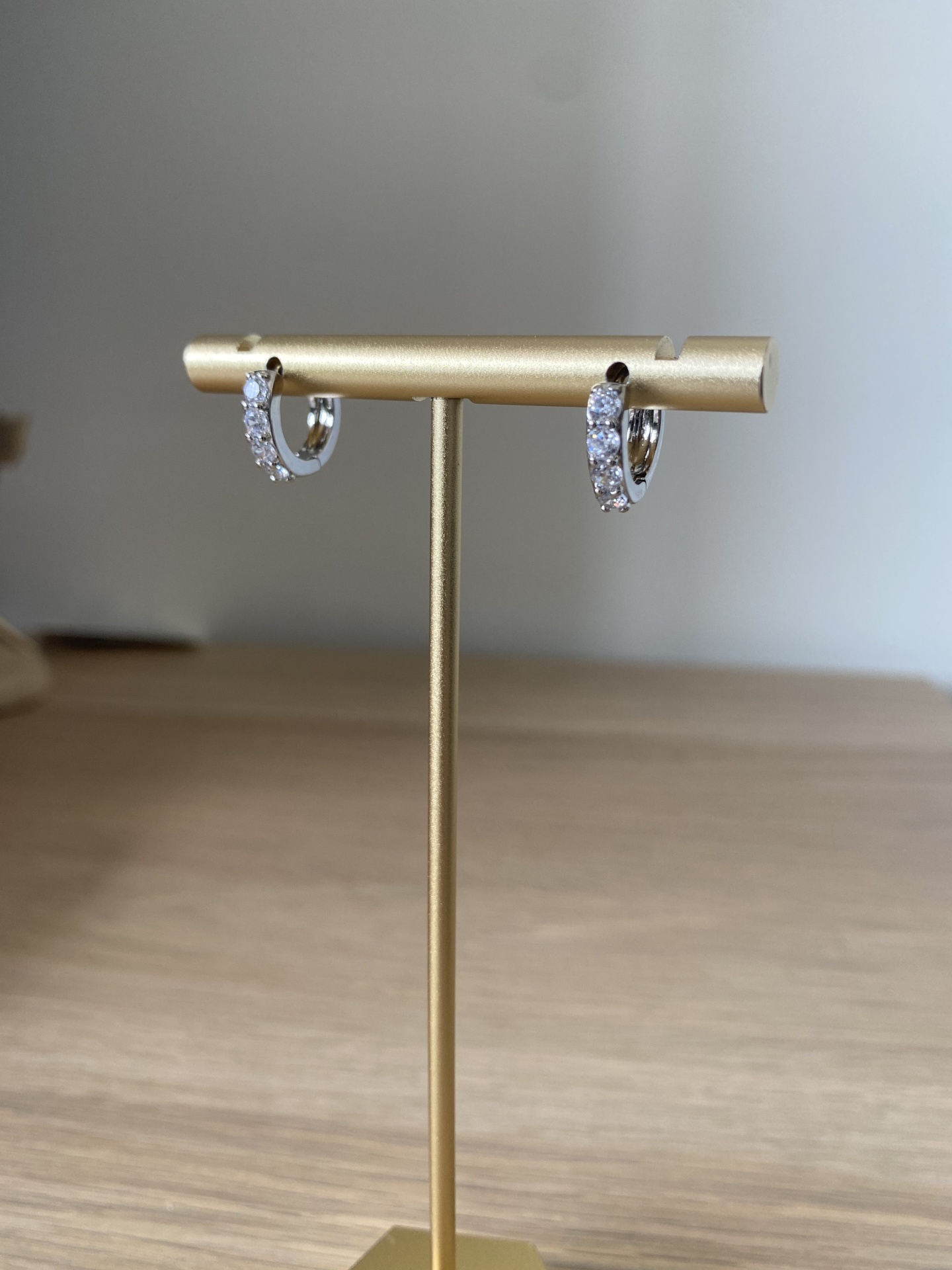 Brincos de argola prateados com pedras num suporte dourado