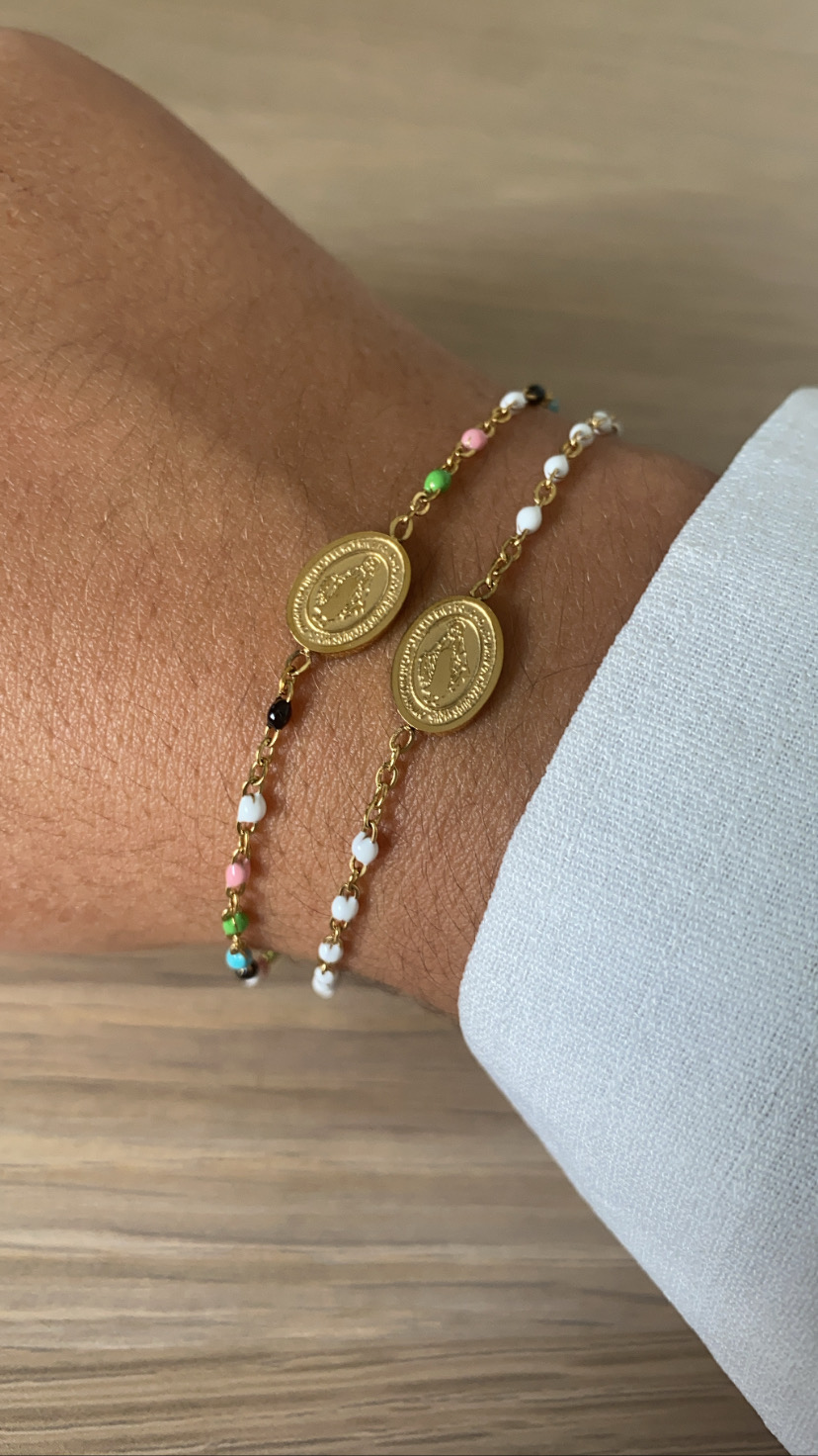 Pulseiras finas coloridas com medalhas douradas no pulso