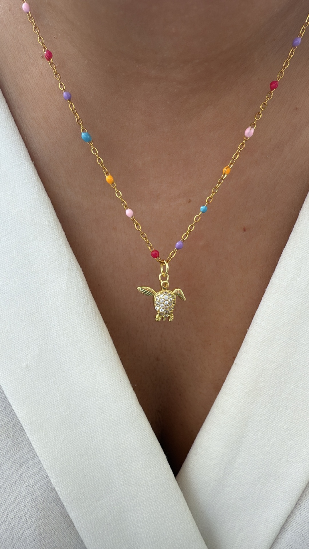 Colar dourado com contas coloridas e pendente de coelho com asas