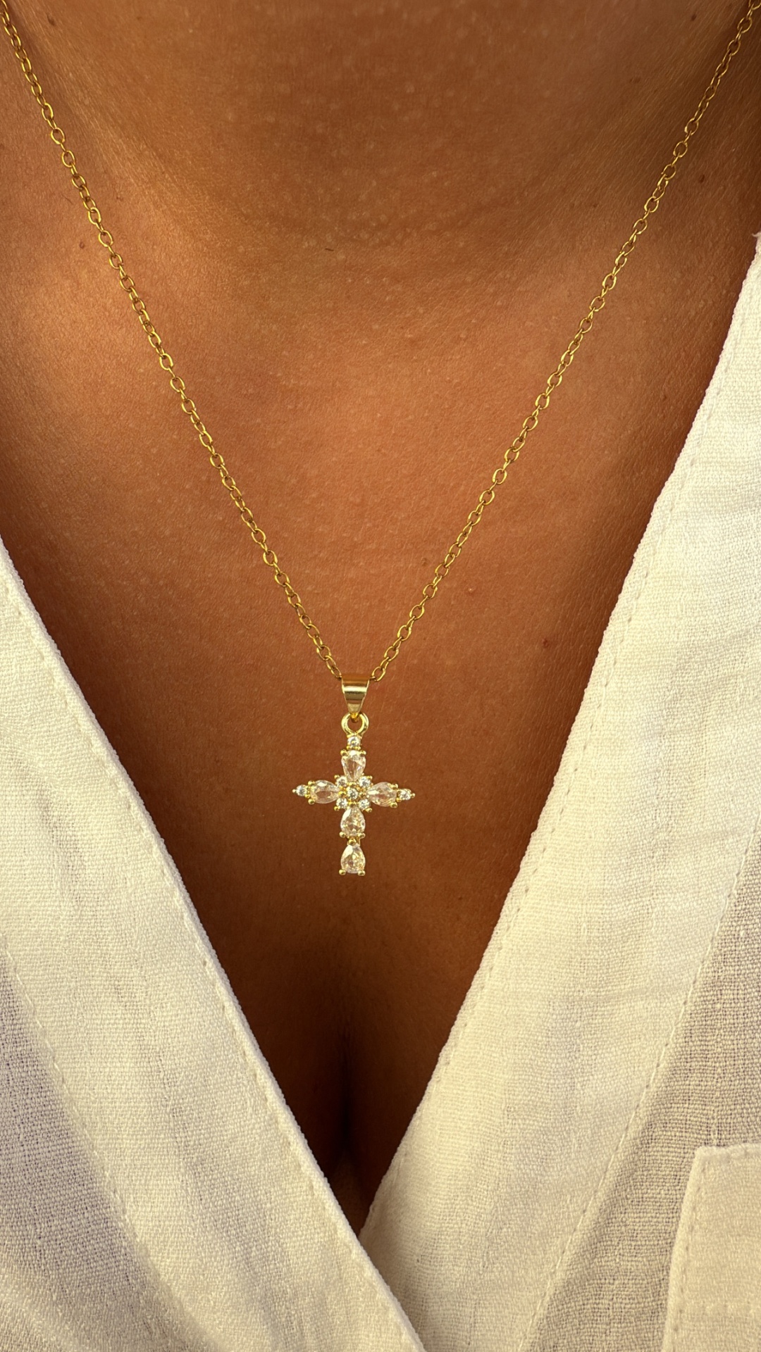 Colar dourado com pendente em forma de cruz com pedras brilhantes