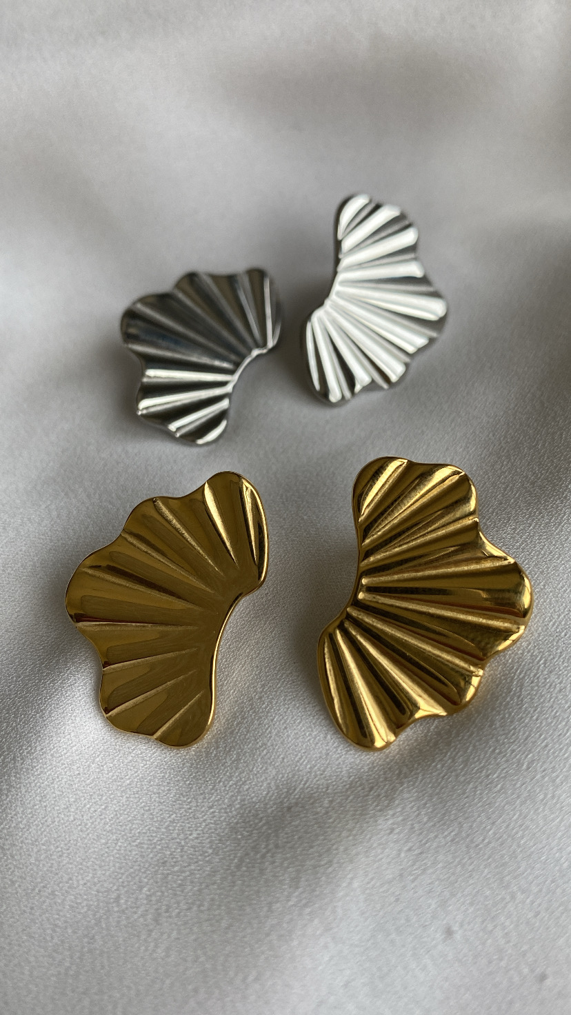 Brincos ondulados dourados e prateados sobre tecido branco