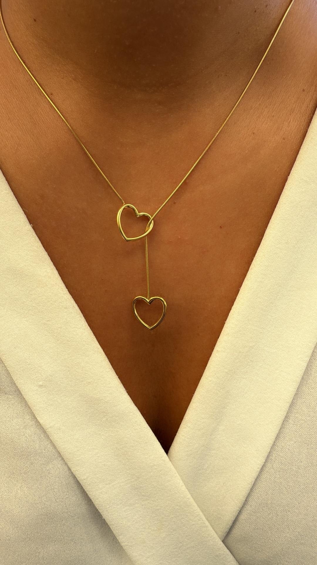 Colar dourado com corações em pescoço com vestido branco