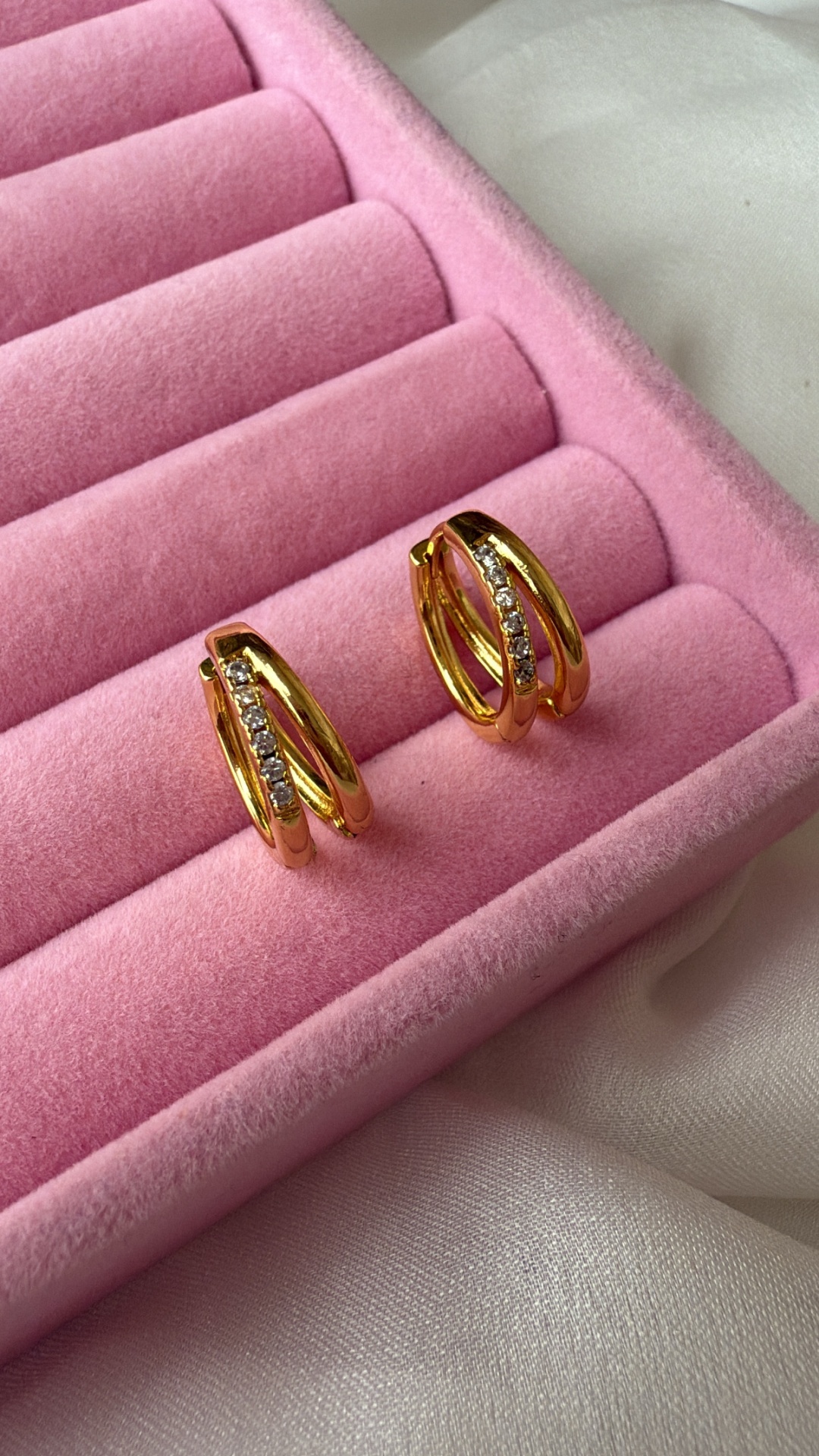 Brincos dourados com pedras em caixa de veludo rosa