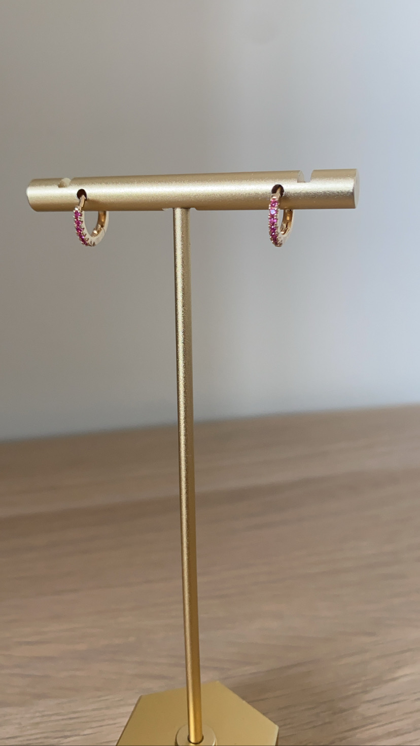 Brincos de argola dourados com pedras rosas num suporte metálico dourado