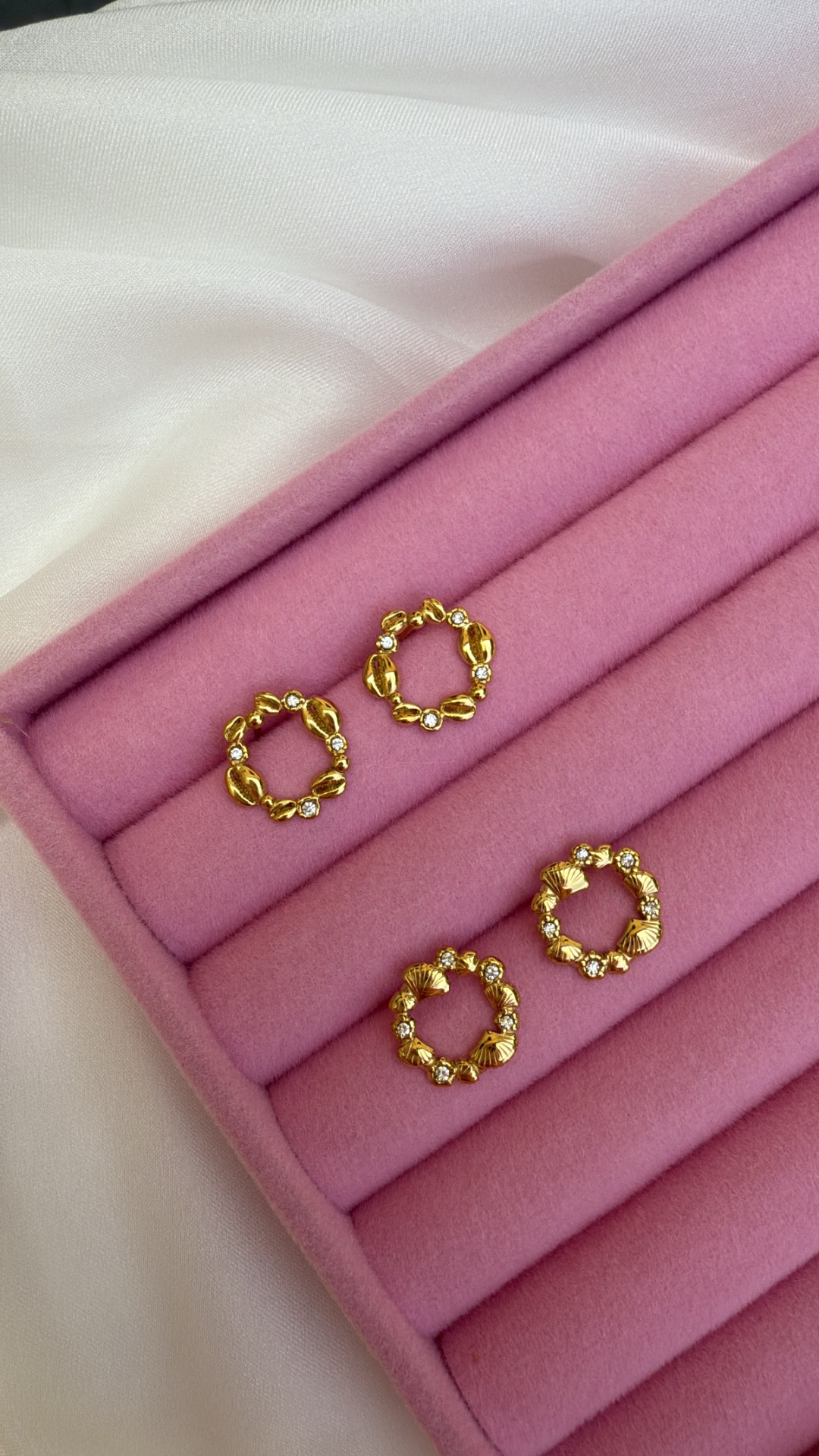 Dois pares de brincos dourados com detalhes em pedras brilhantes em caixa de veludo rosa