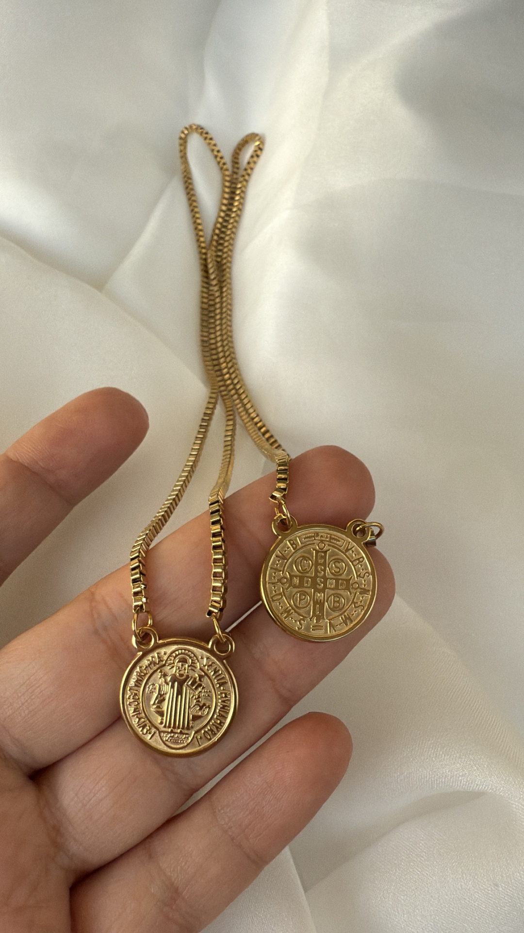 Colares com medalhões dourados e correntes finas sobre fundo branco