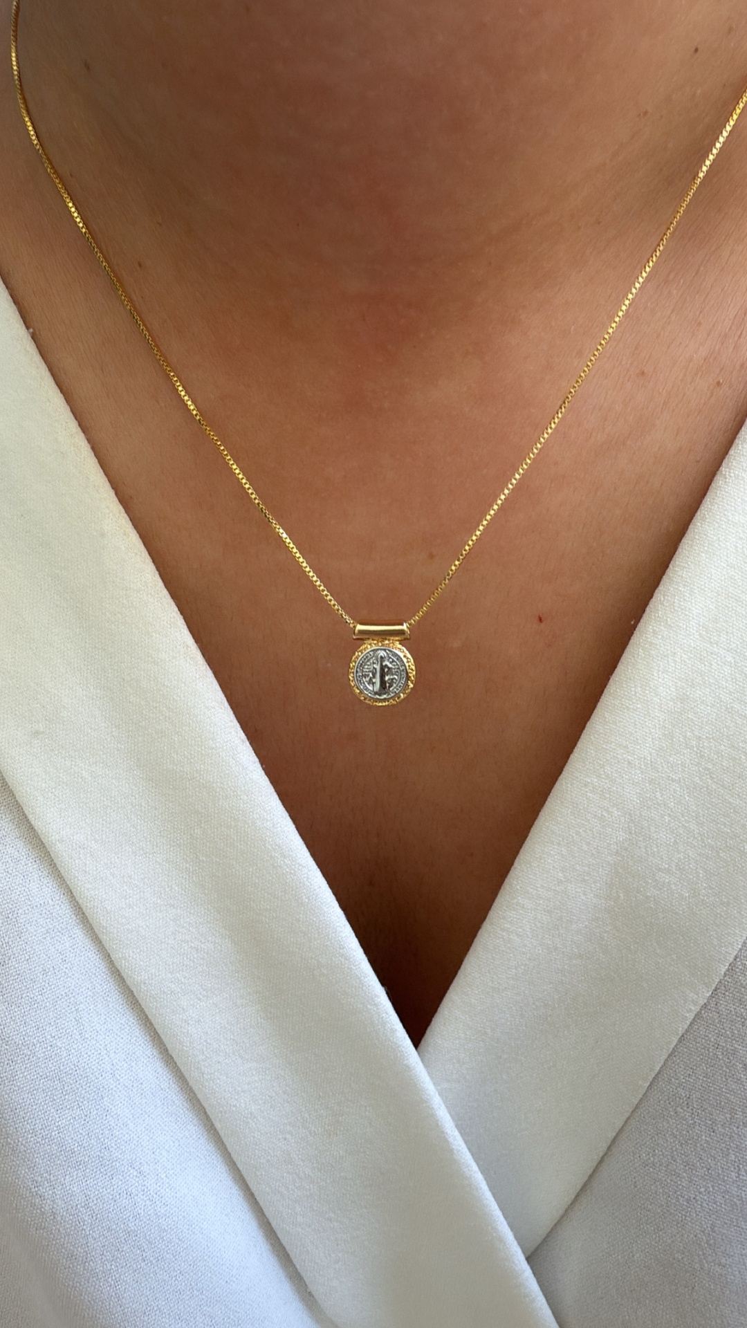 Colar dourado com pendente redondo prateado no pescoço