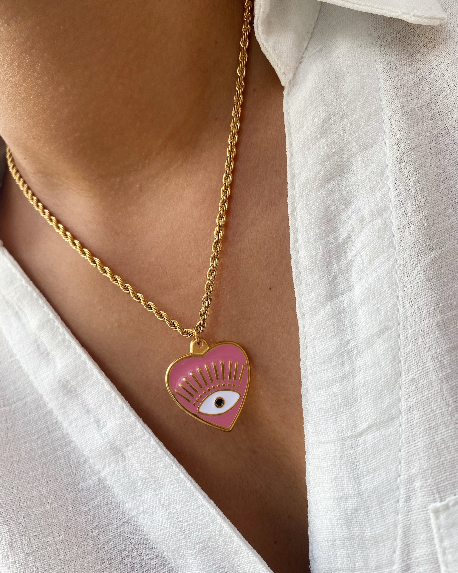 Colar dourado com pendente coração rosa e olho estilizado