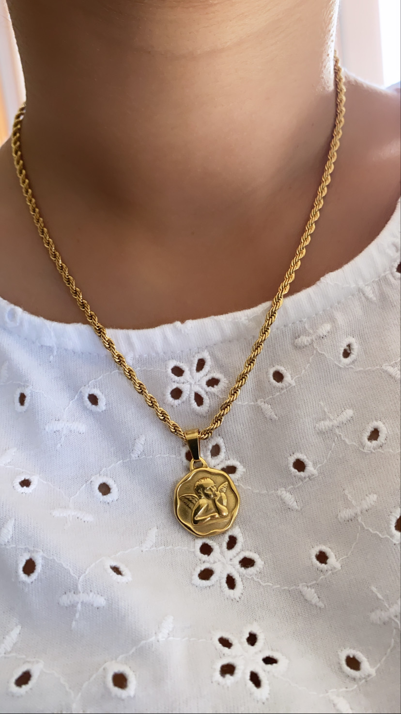 Colar dourado com pendente redondo e blusa branca bordada