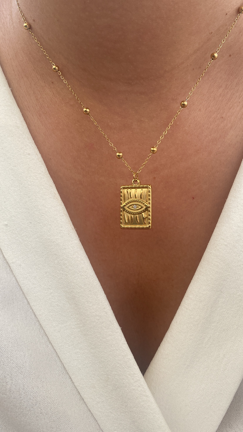 Colar dourado com pendente retangular e olho estilizado em relevo
