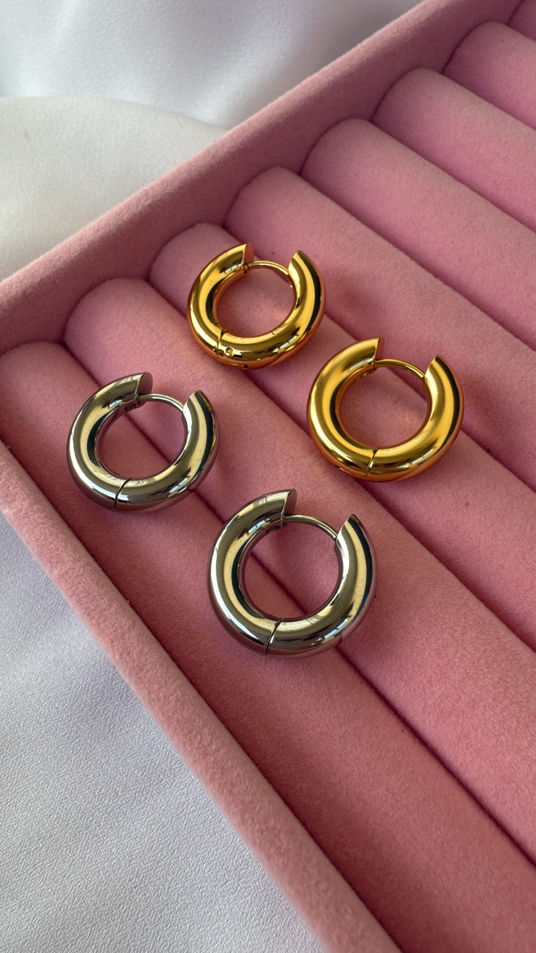 Brincos argola dourados e prateados em caixa rosa de veludo