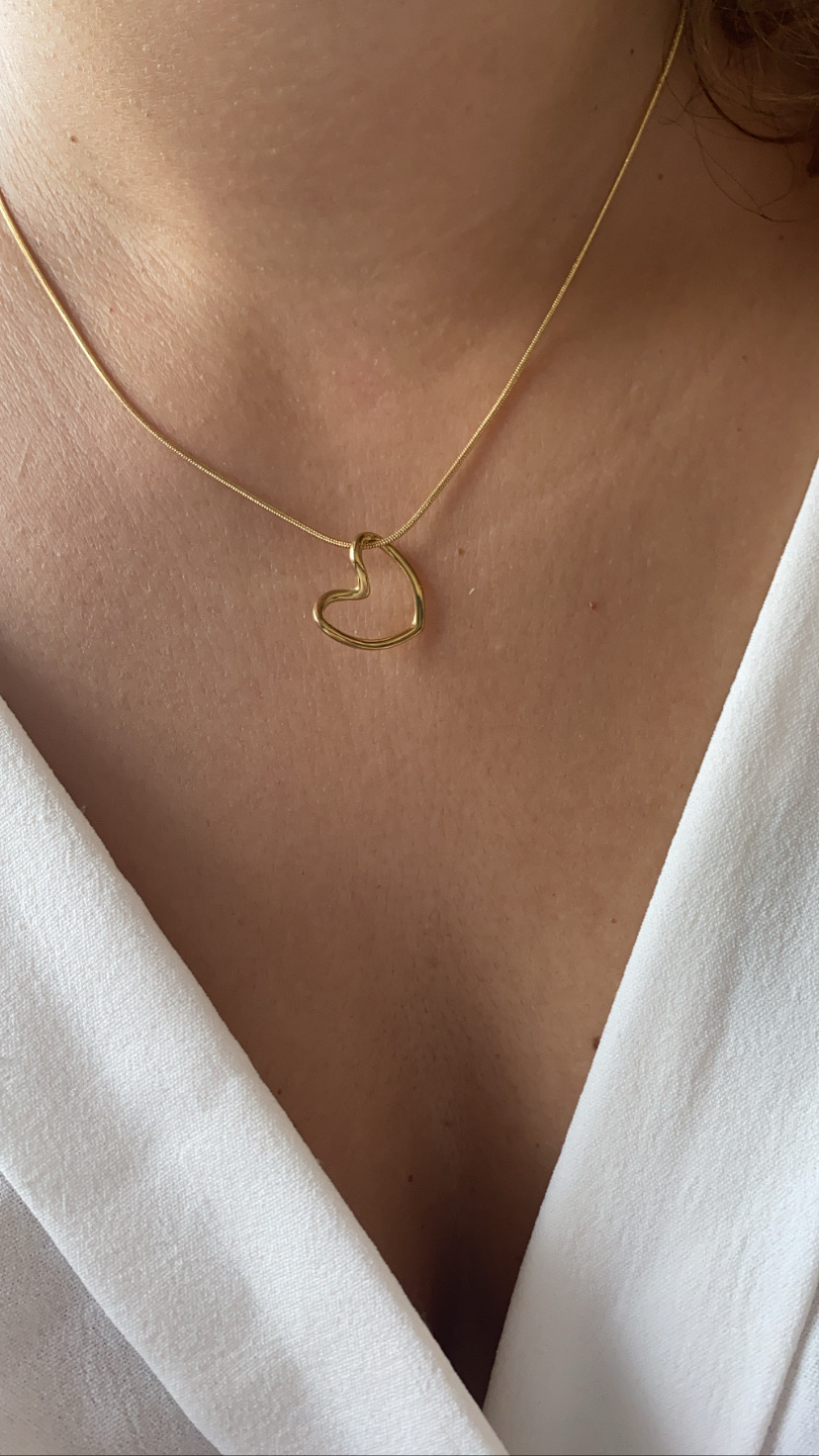 Colar dourado com coração abstrato e blusa branca