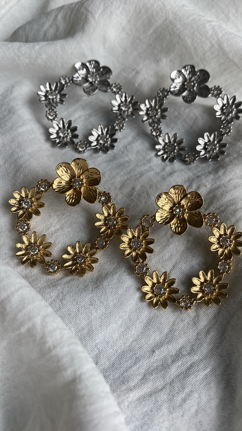 Brincos redondos florais em metal dourado e prateado sobre tecido branco