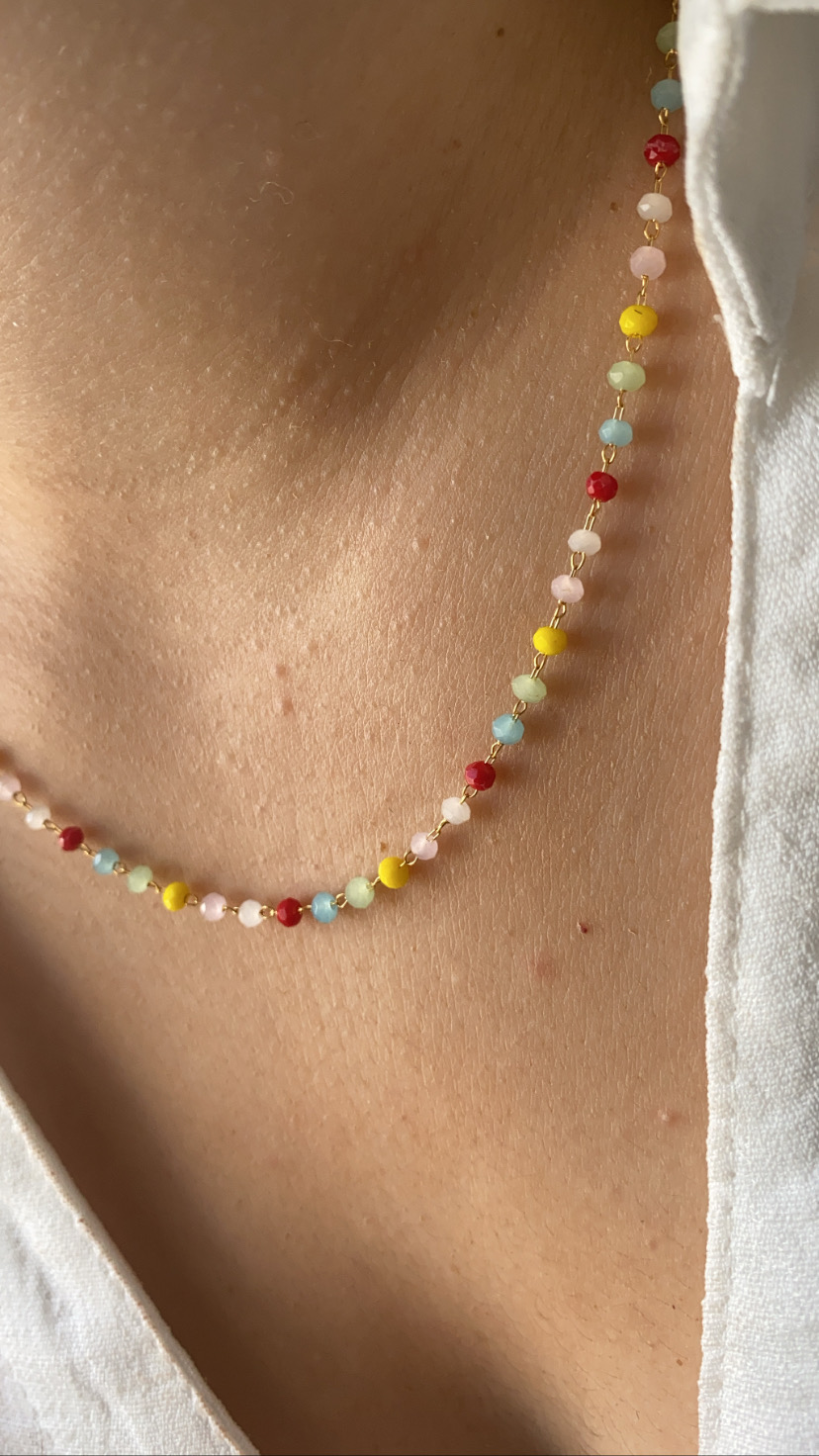 Colar de contas coloridas usado no pescoço com roupa branca
