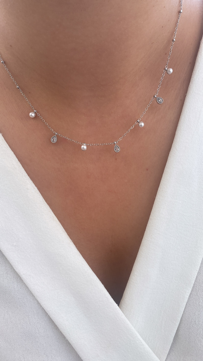 Colar prateado com pérolas e gotas brilhantes sobre camisa branca