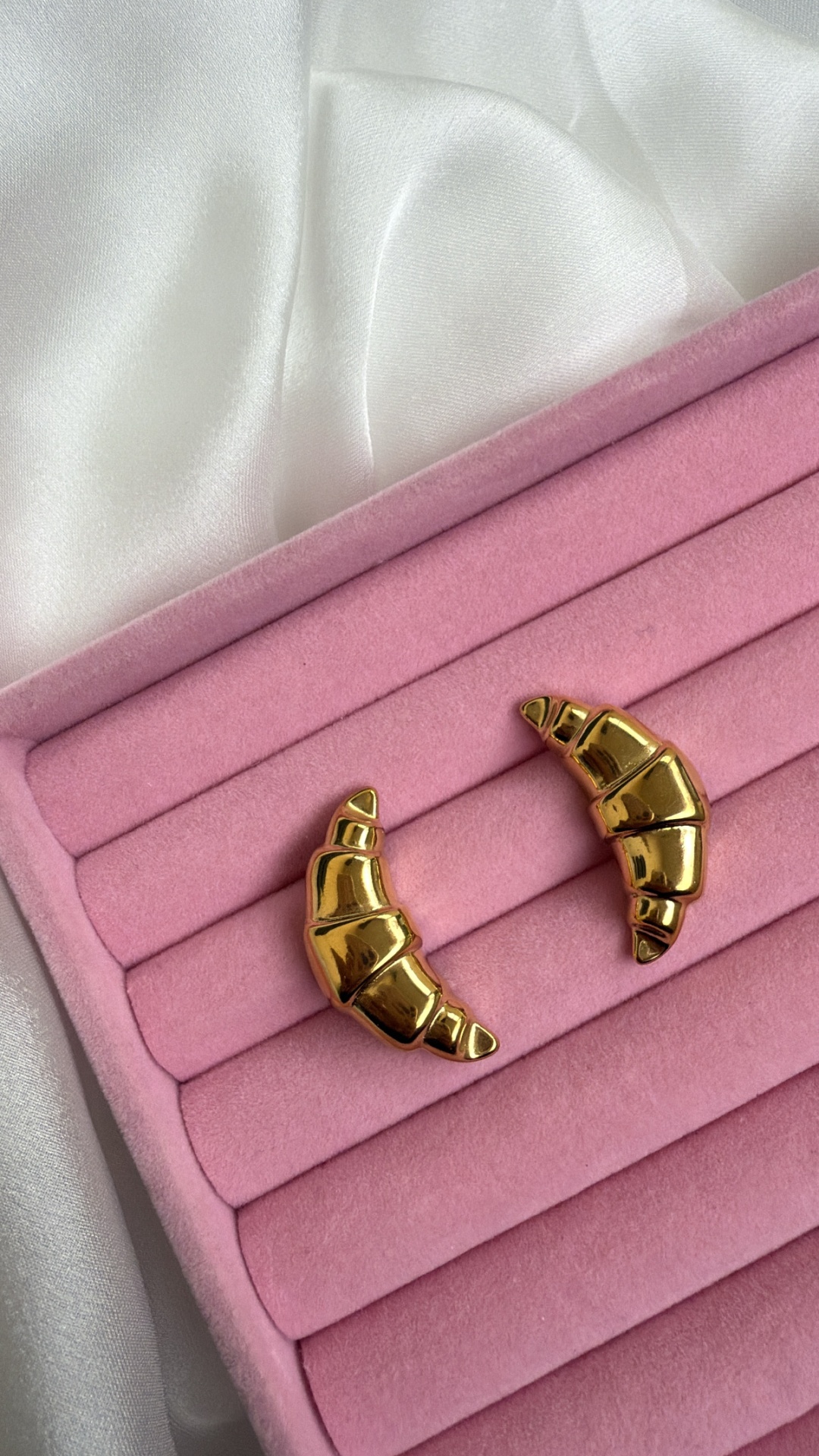 Brincos dourados croissant em almofada rosa de veludo