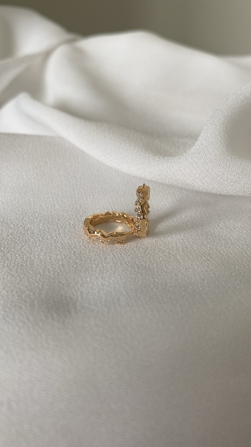 Anel dourado com pedras sobre tecido branco suave