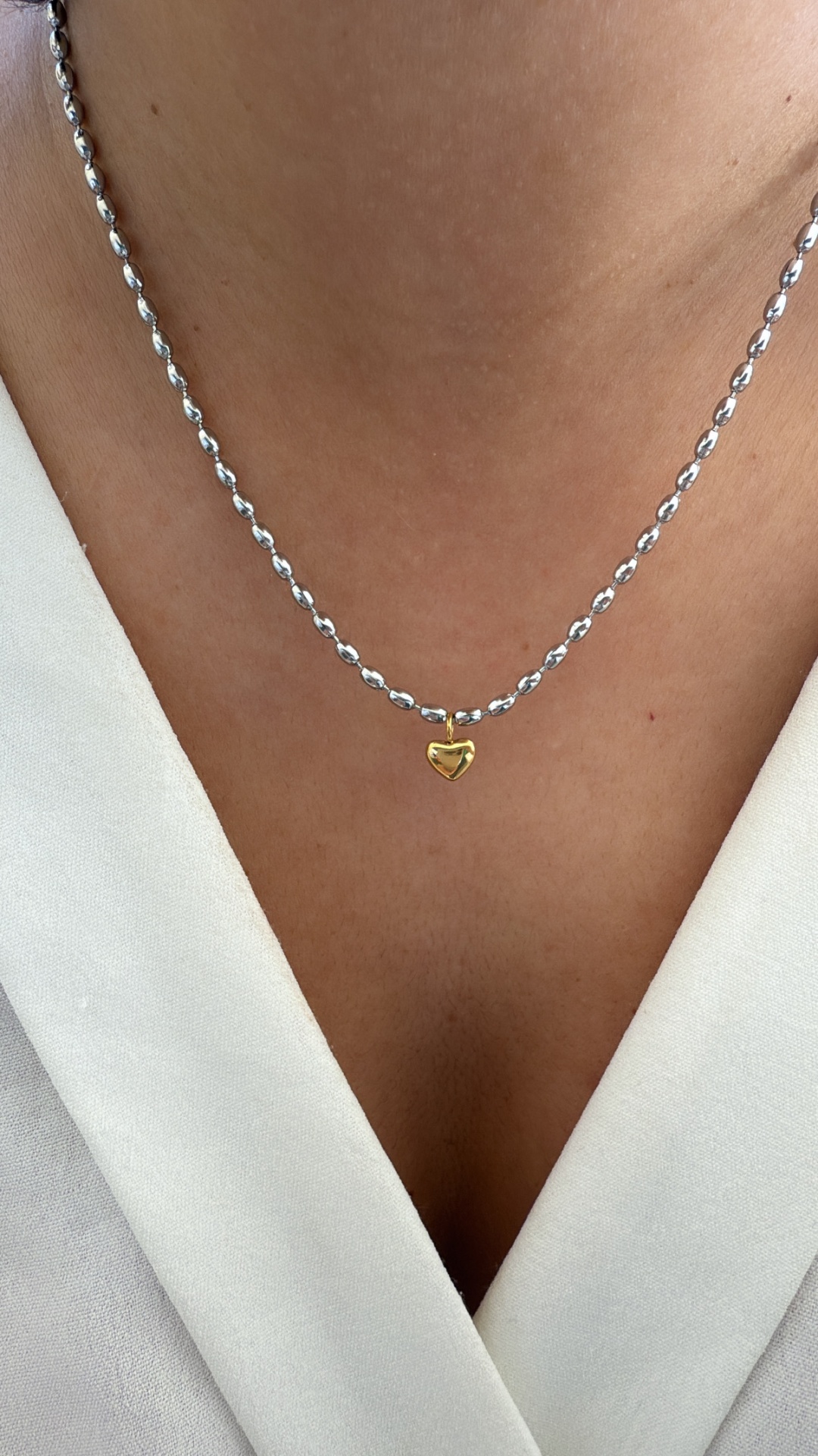 Colar com corrente prateada e pendente de coração dourado