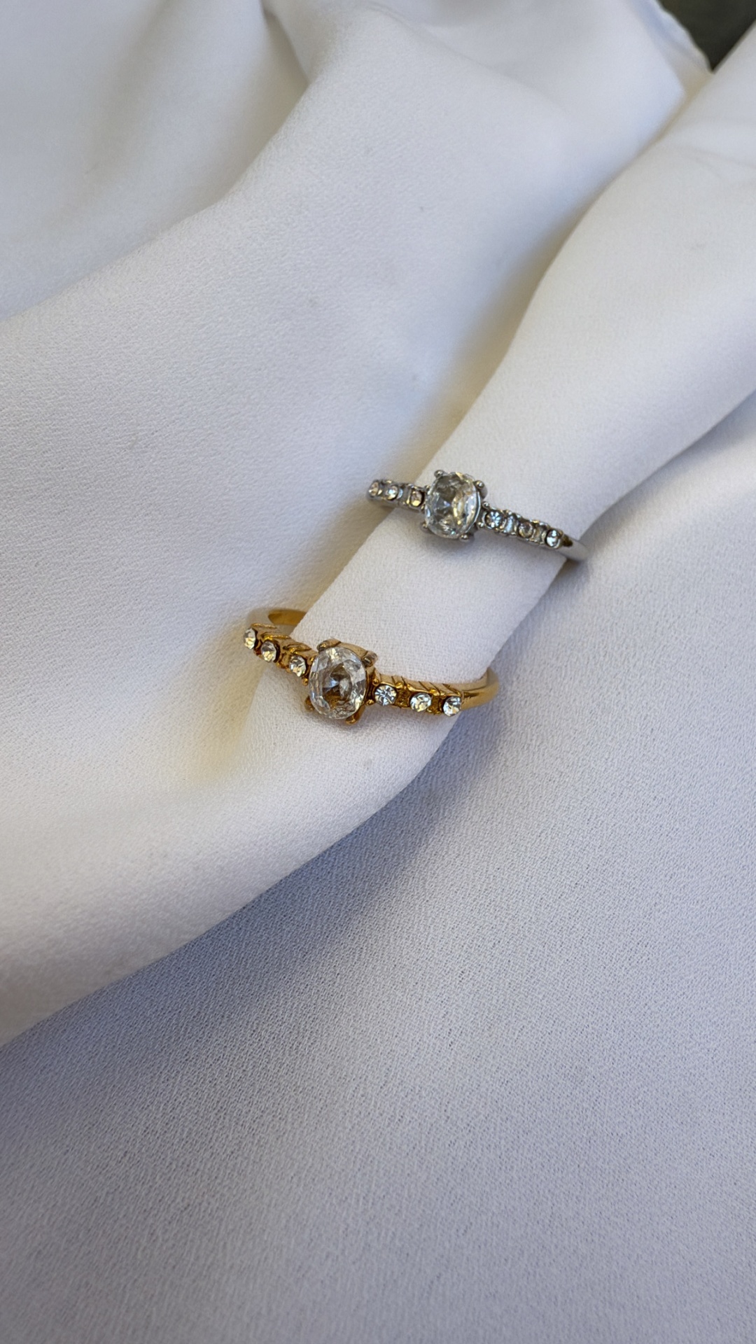 Anéis finos dourado e prateado com pedras sobre tecido branco