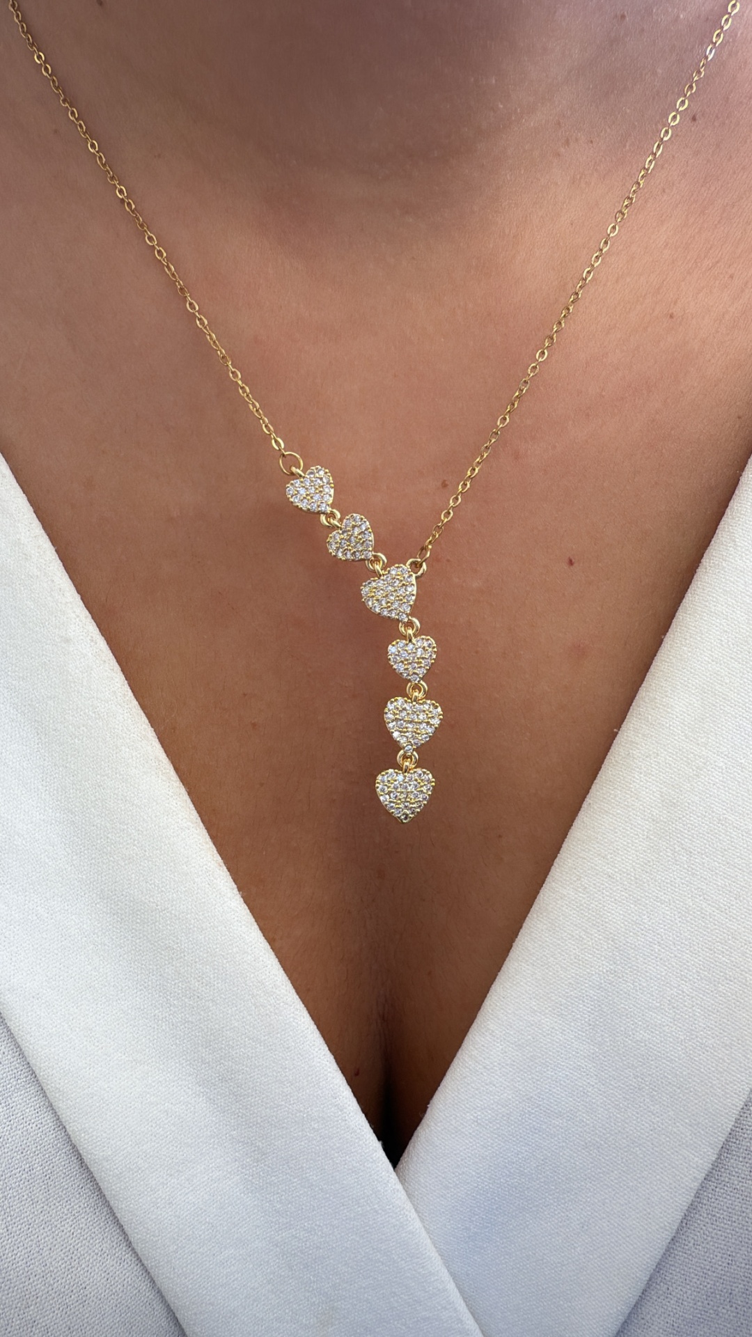 Colar dourado com sete corações brilhantes em pele com decote em V branco