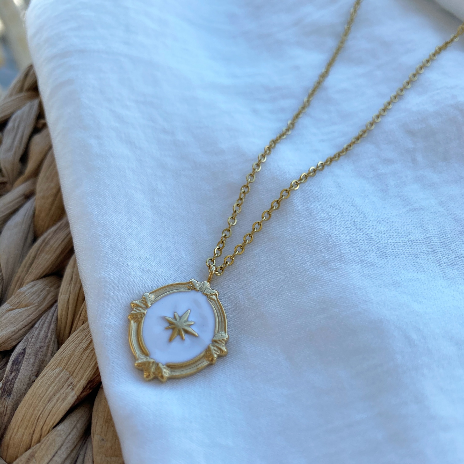 Colar dourado com pendente circular e pedra branca com estrela