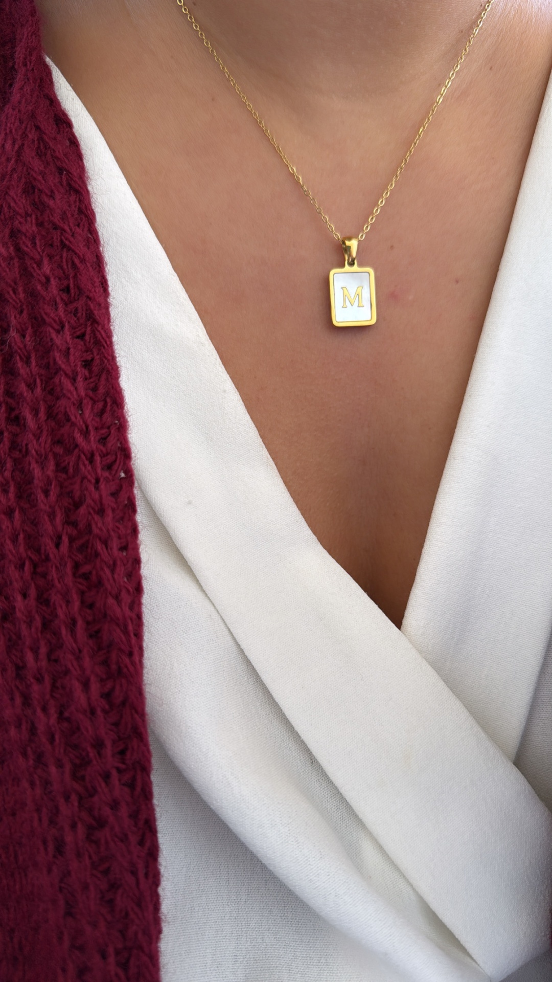 Colar dourado com pendente retangular branco e letra M