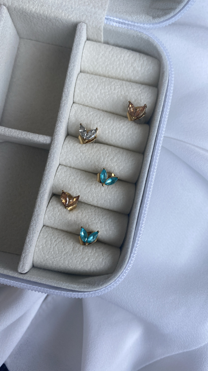 Conjunto de cinco anéis dourados com pedras coloridas em caixa branca aveludada