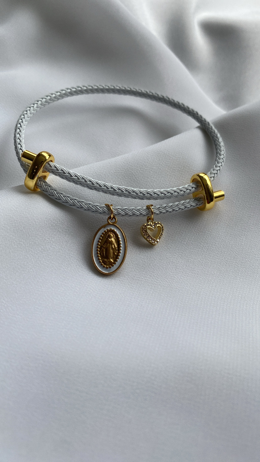 Pulseira dupla branca com pendentes dourados em fundo branco.