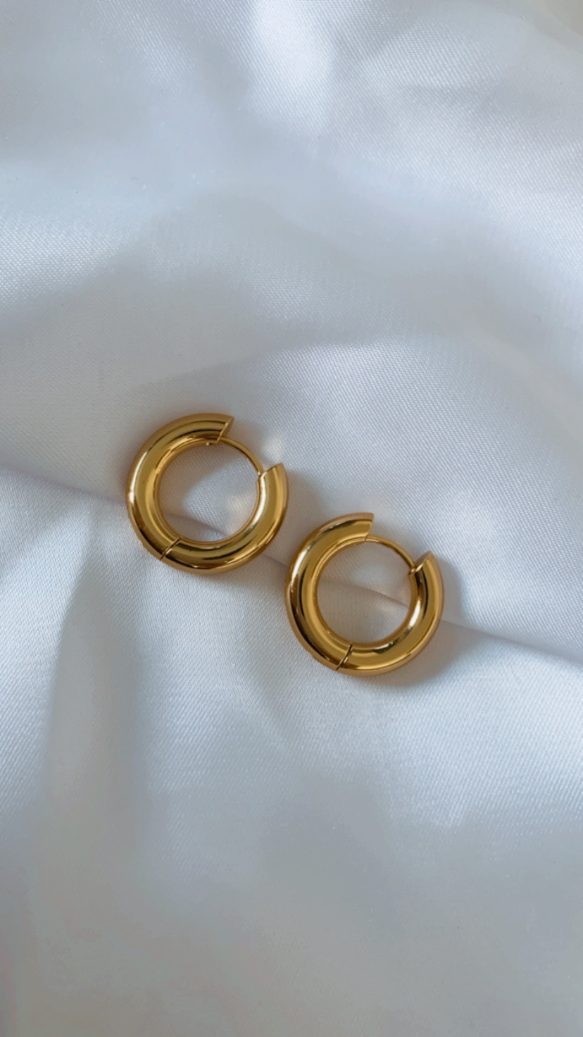 Brincos de argola dourados sobre tecido branco