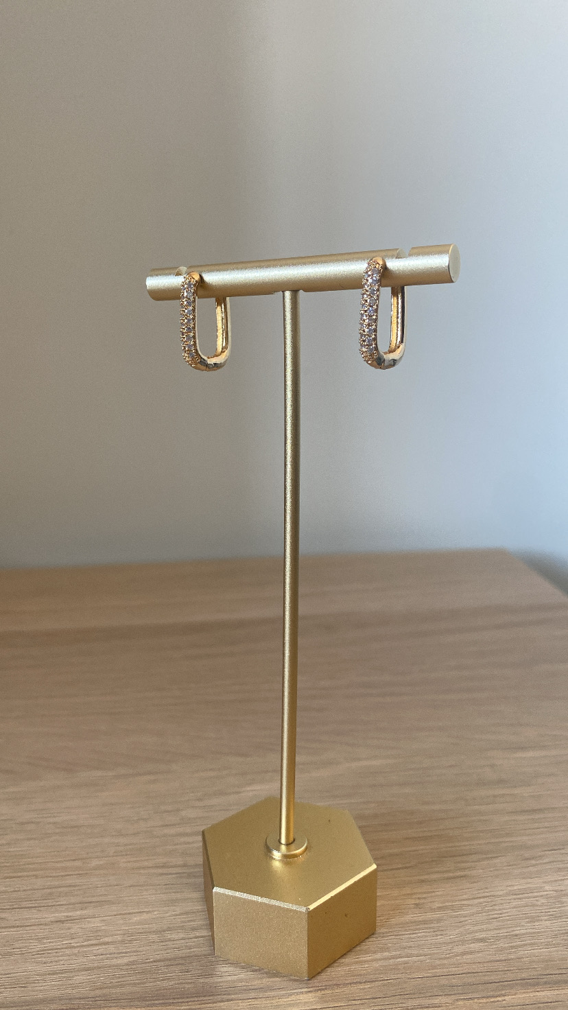 Brincos argola dourados com pedras brilhantes num suporte dourado