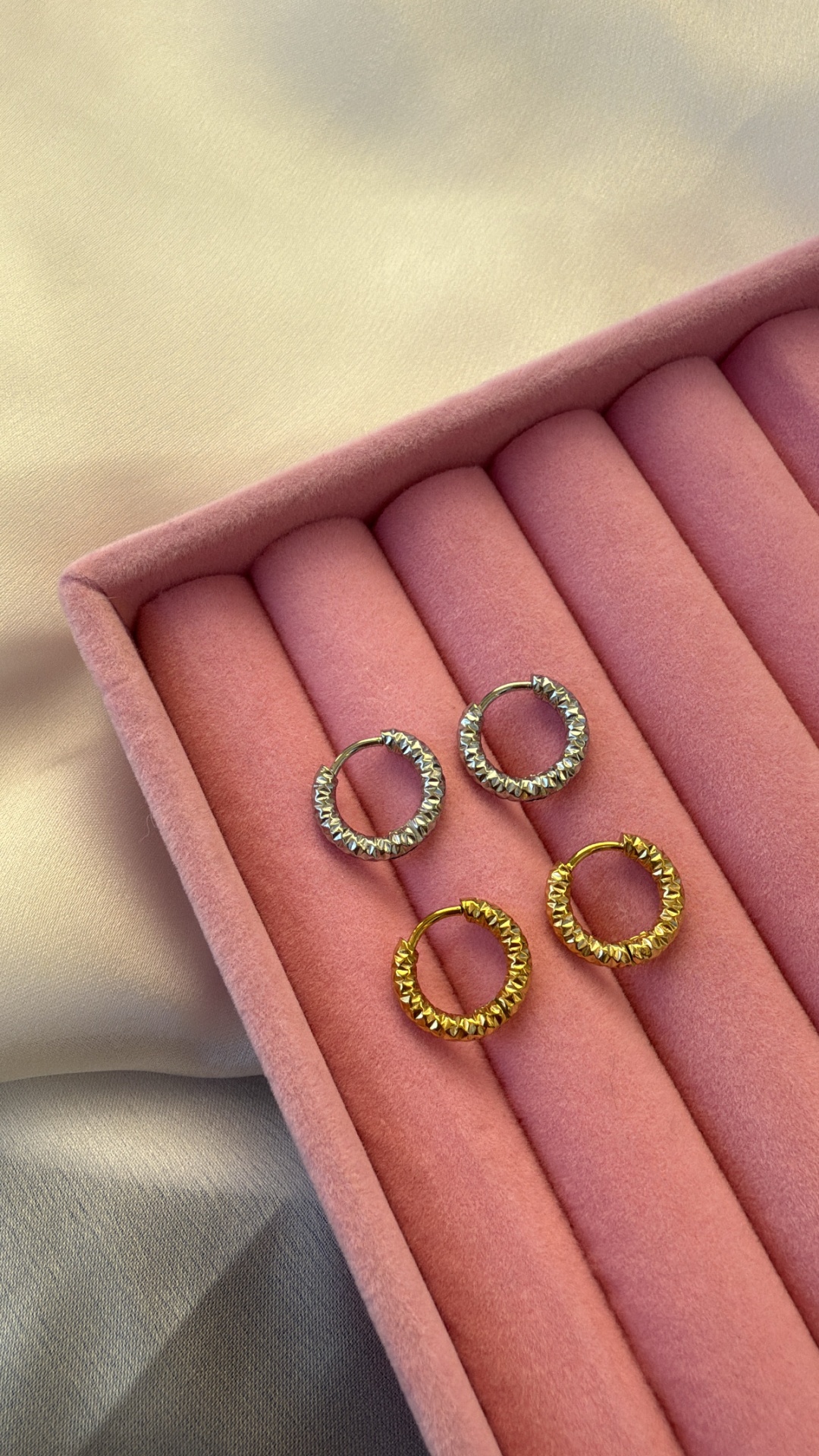 Dois pares de brincos de aro prateado e dourado em caixa rosa