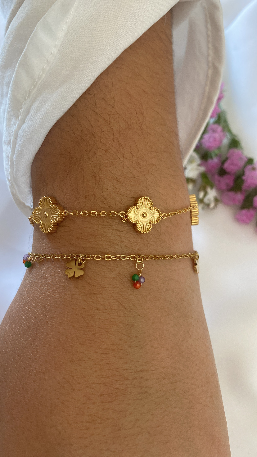 Duas pulseiras douradas delicadas num pulso com manga branca