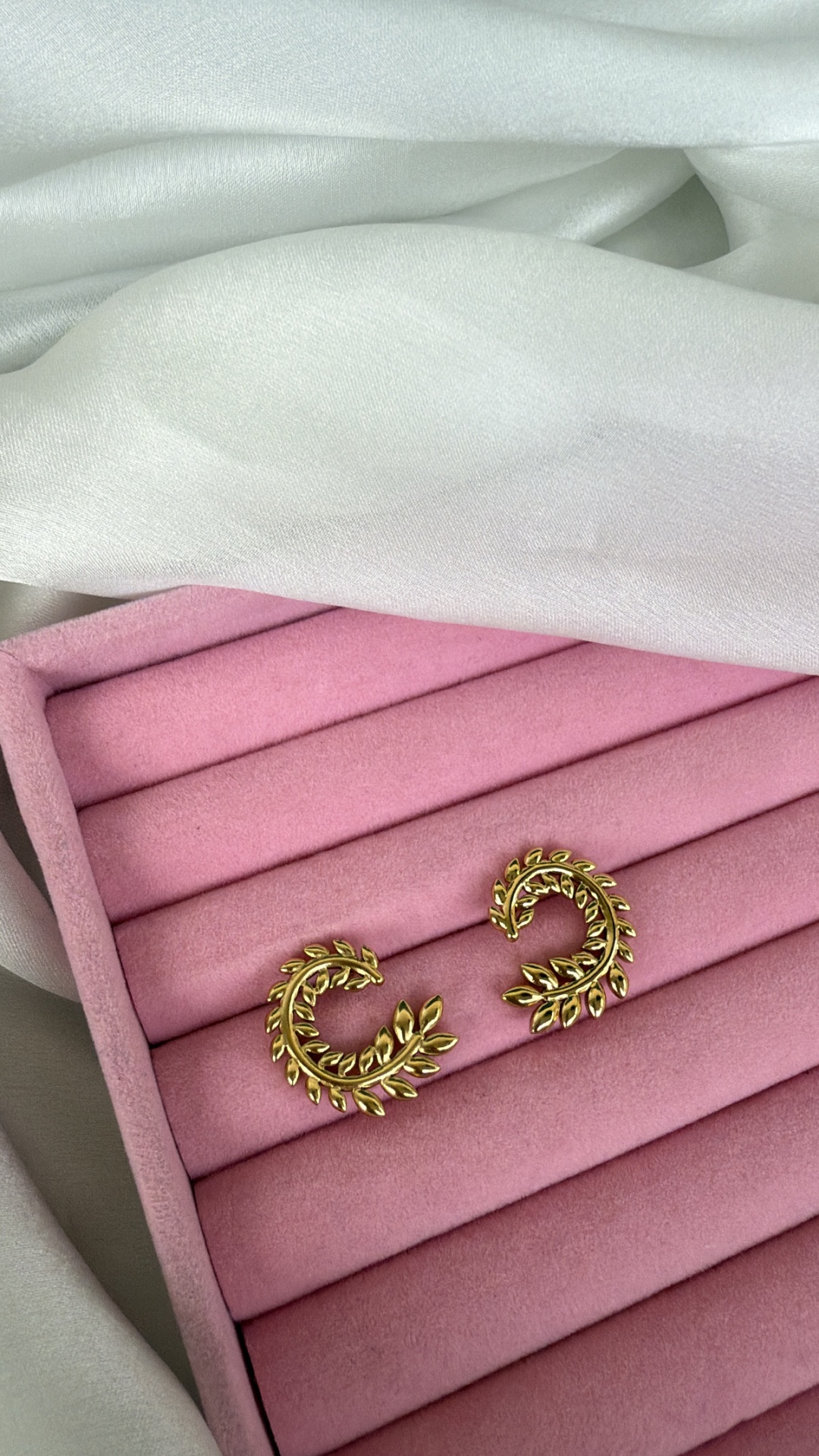 Brincos dourados em forma de folhas em caixa rosa de veludo