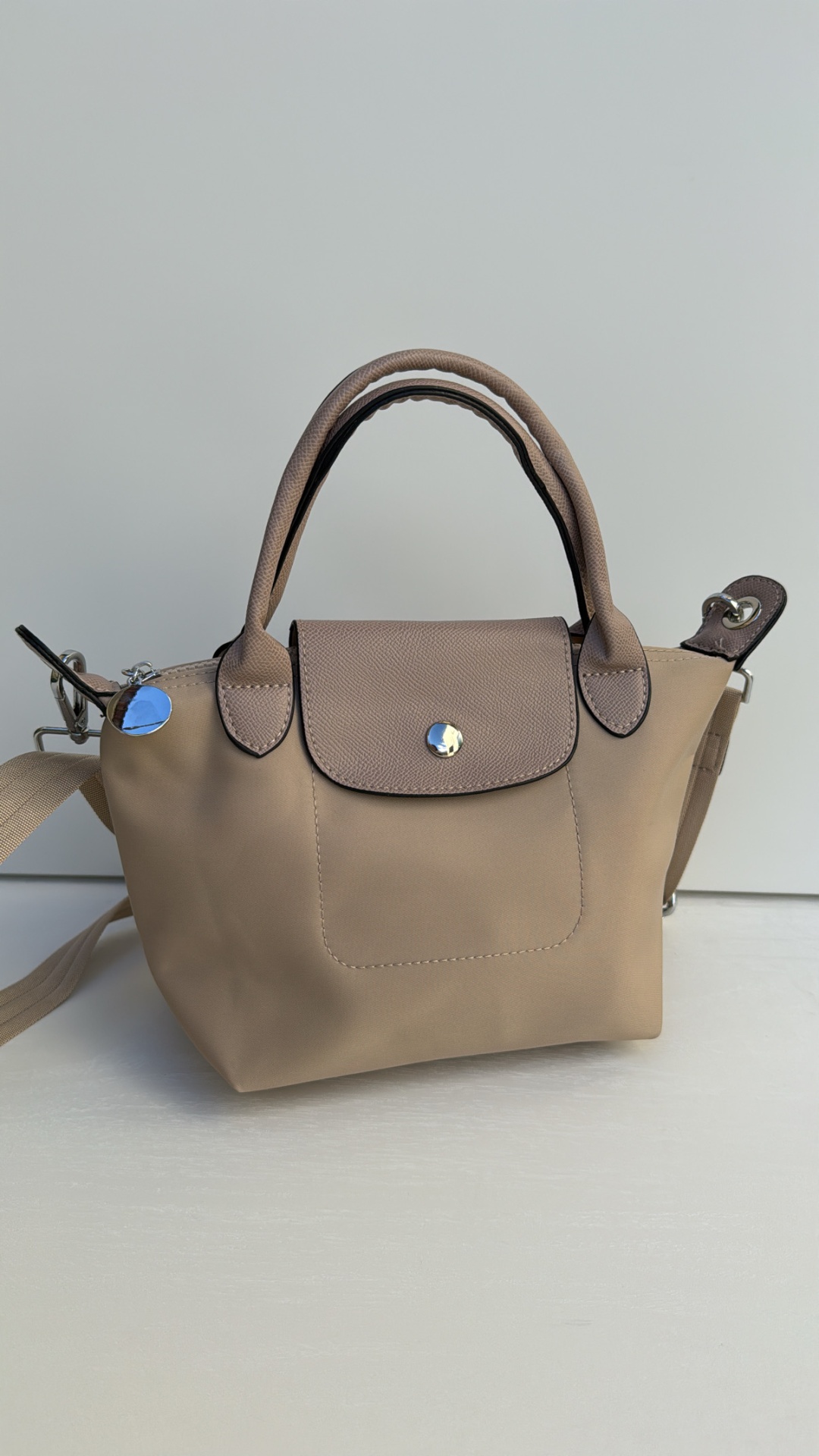 Mala pequena bege com alças castanhas e botão prateado