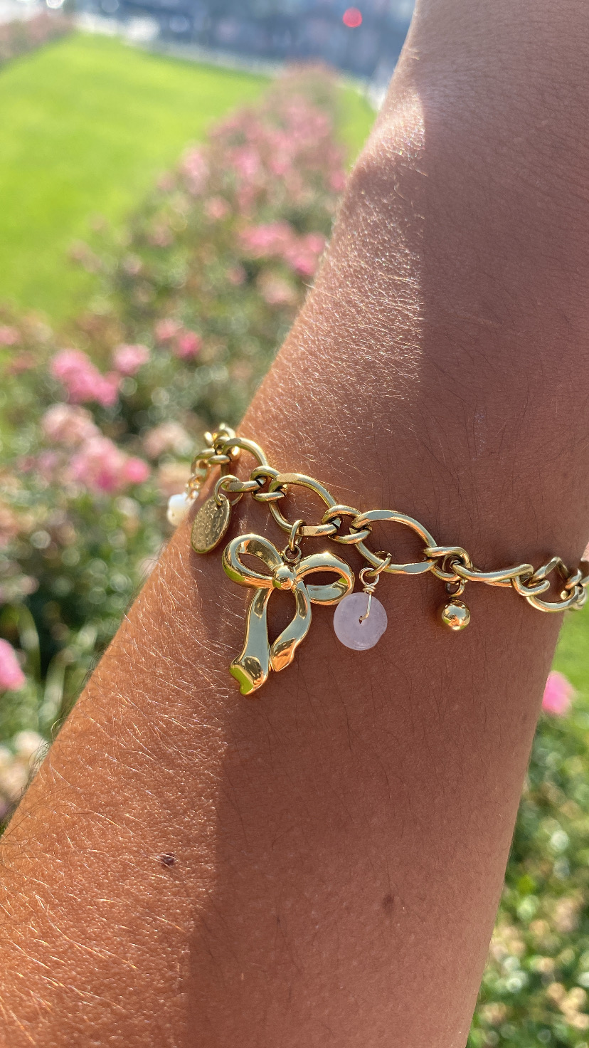 Pulseira dourada com pendentes num pulso ao ar livre